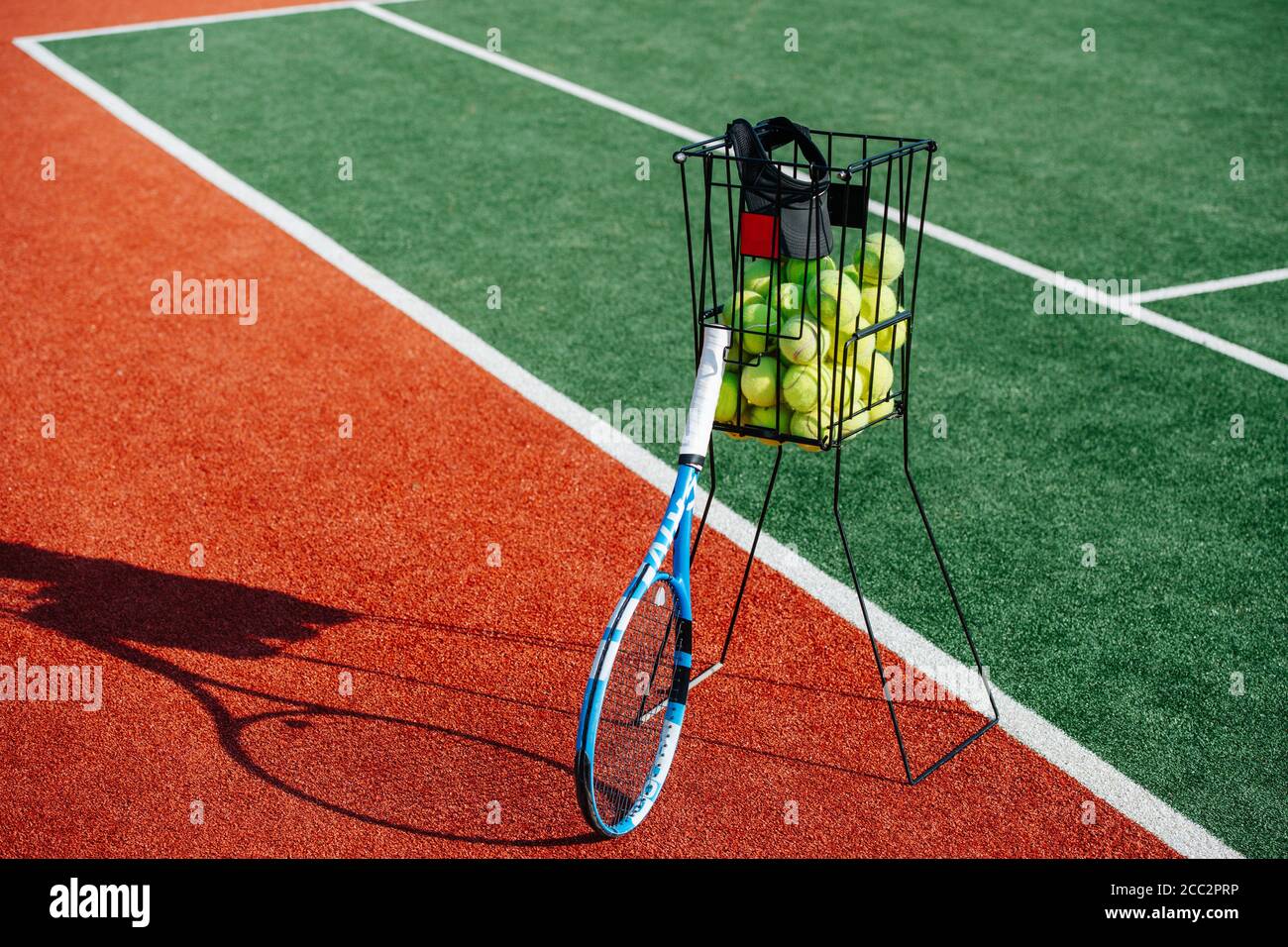 Tennis ball basket and a racket next to green inner court zone Stock ...