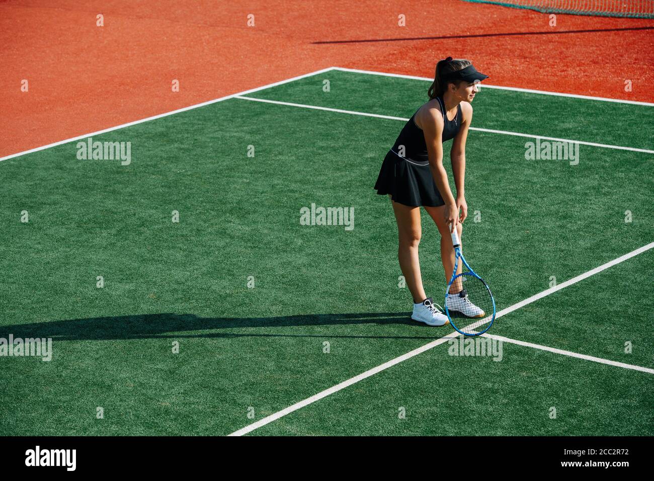 Resting girl playing tennis on a new court, leaning on a racket Stock Photo