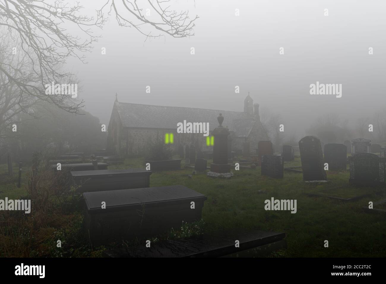 In this fantasy image of St Beuno's Church in Trefdraeth, Anglesey, the fog has been emphasised and eerie light placed in the windows. Stock Photo