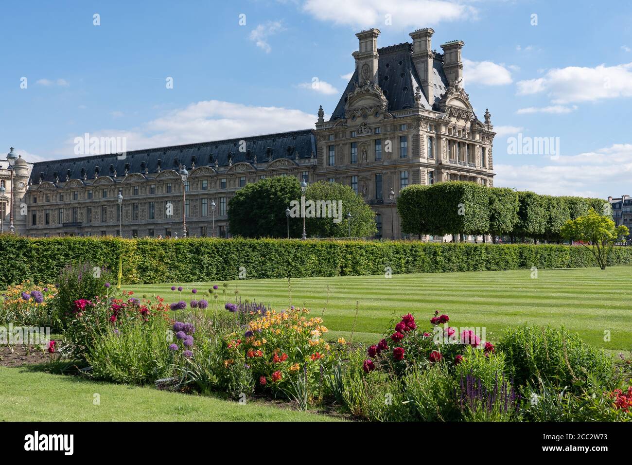 Pavillon de Marsan. Louvre palace museum with park, lawn and flowers at hot sunny day. Jardin des tuileries. Paris - France, 31. may 2019 Stock Photo
