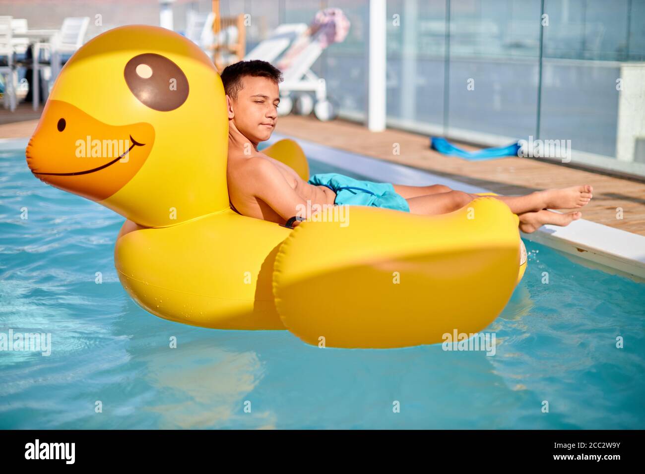 little boy is relaxing on Yellow Duck at pool. Background of travel in summer holiday Stock Photo
