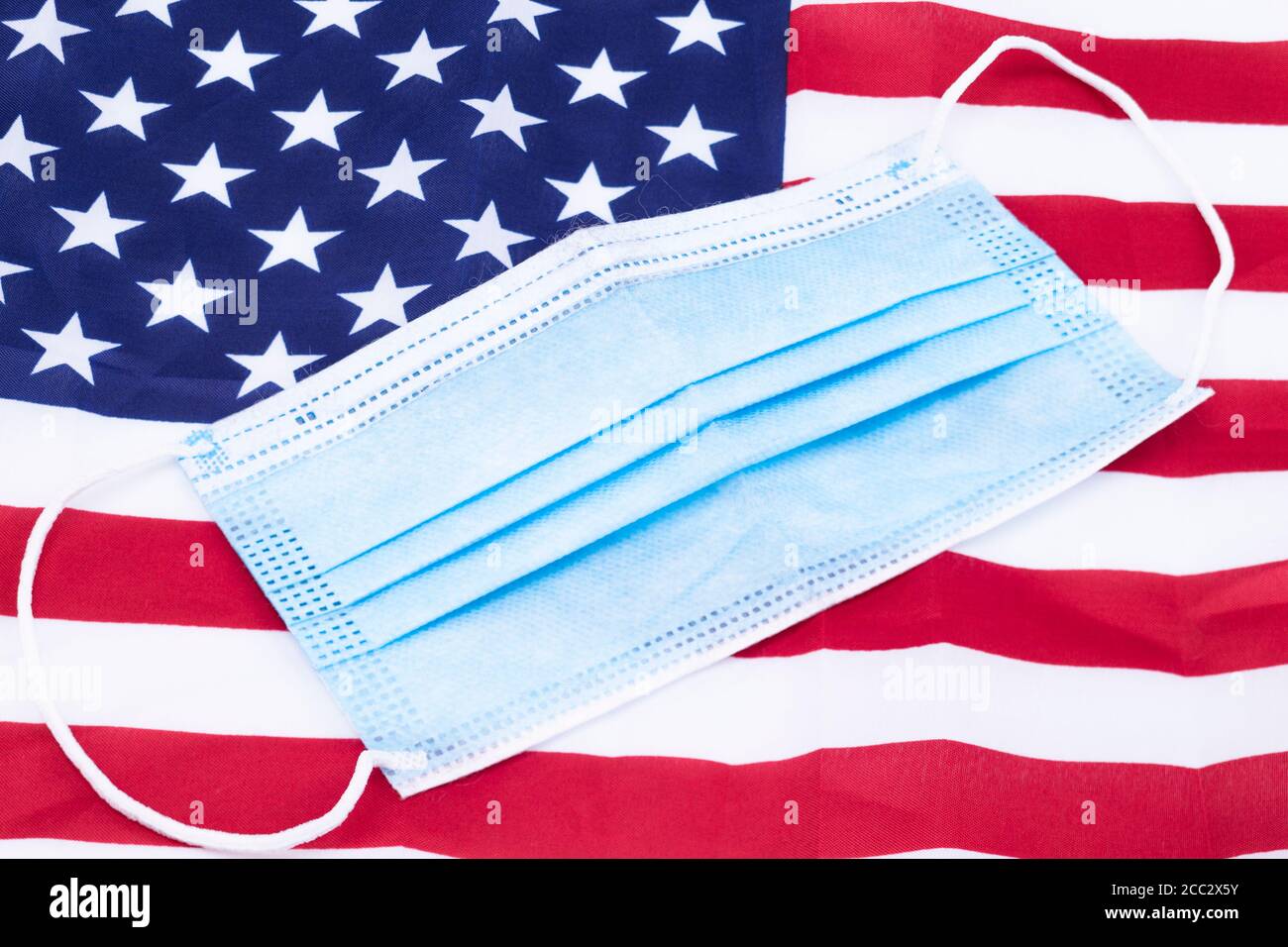 The image shows a flag of the United States of America with a mouth and nose guard Stock Photo