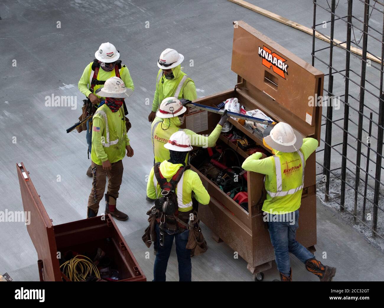 Construction workers wearing safety gear and face coverings gather