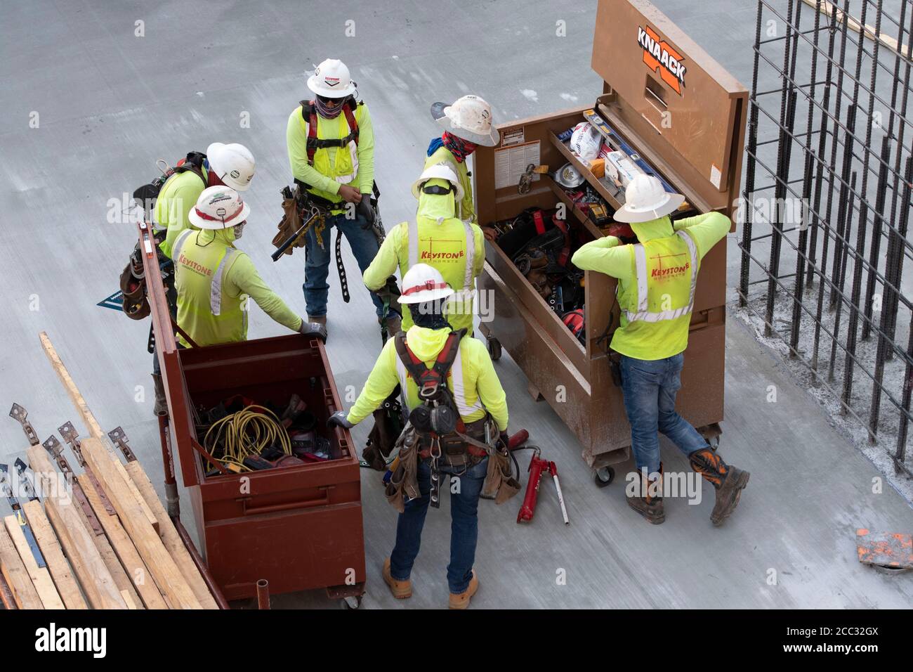 Construction workers wearing safety gear and face coverings gather