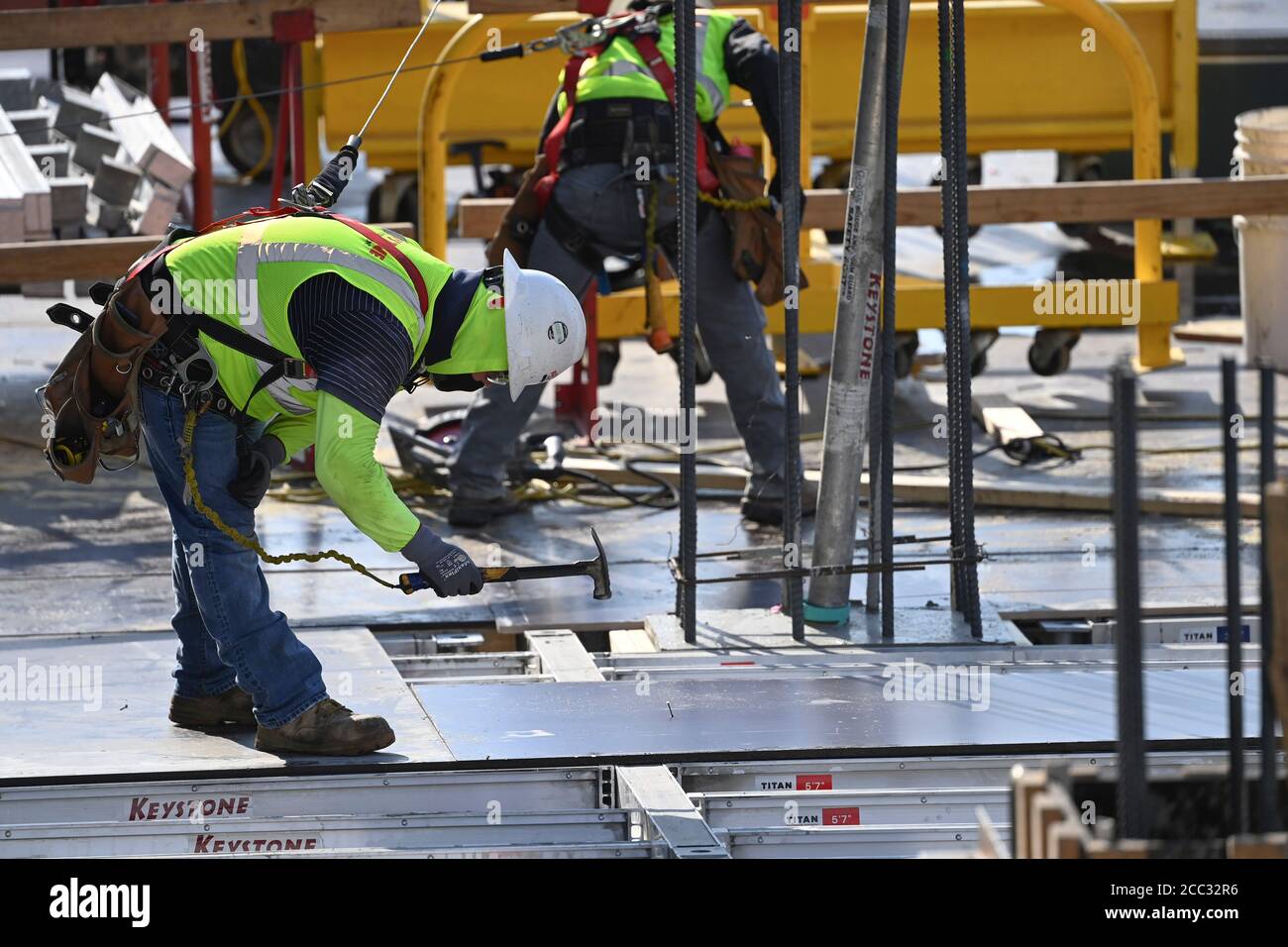 Construction workers wearing safety gear and face coverings team up on