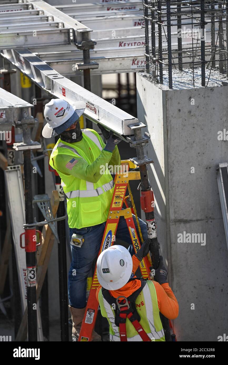 Construction workers wearing safety gear and face coverings team up on