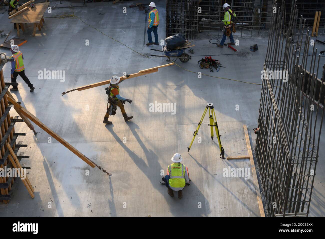 Construction workers wearing safety gear and face coverings perform