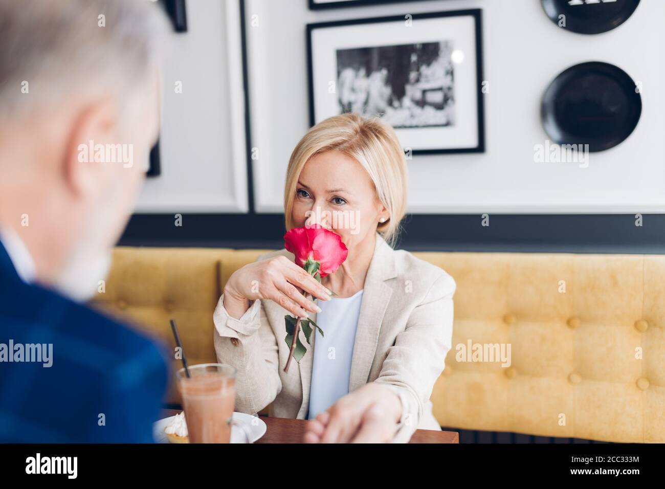 gentleman pays compliments to blond attractive woman and showing his warm feeling while having breakfast in the cafe. the smell of love Stock Photo