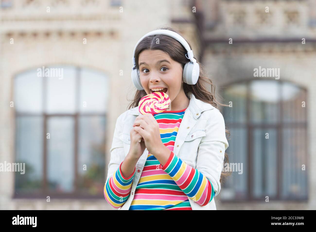 Girl wireless headphones eat lollipop candy, appetite concept Stock ...