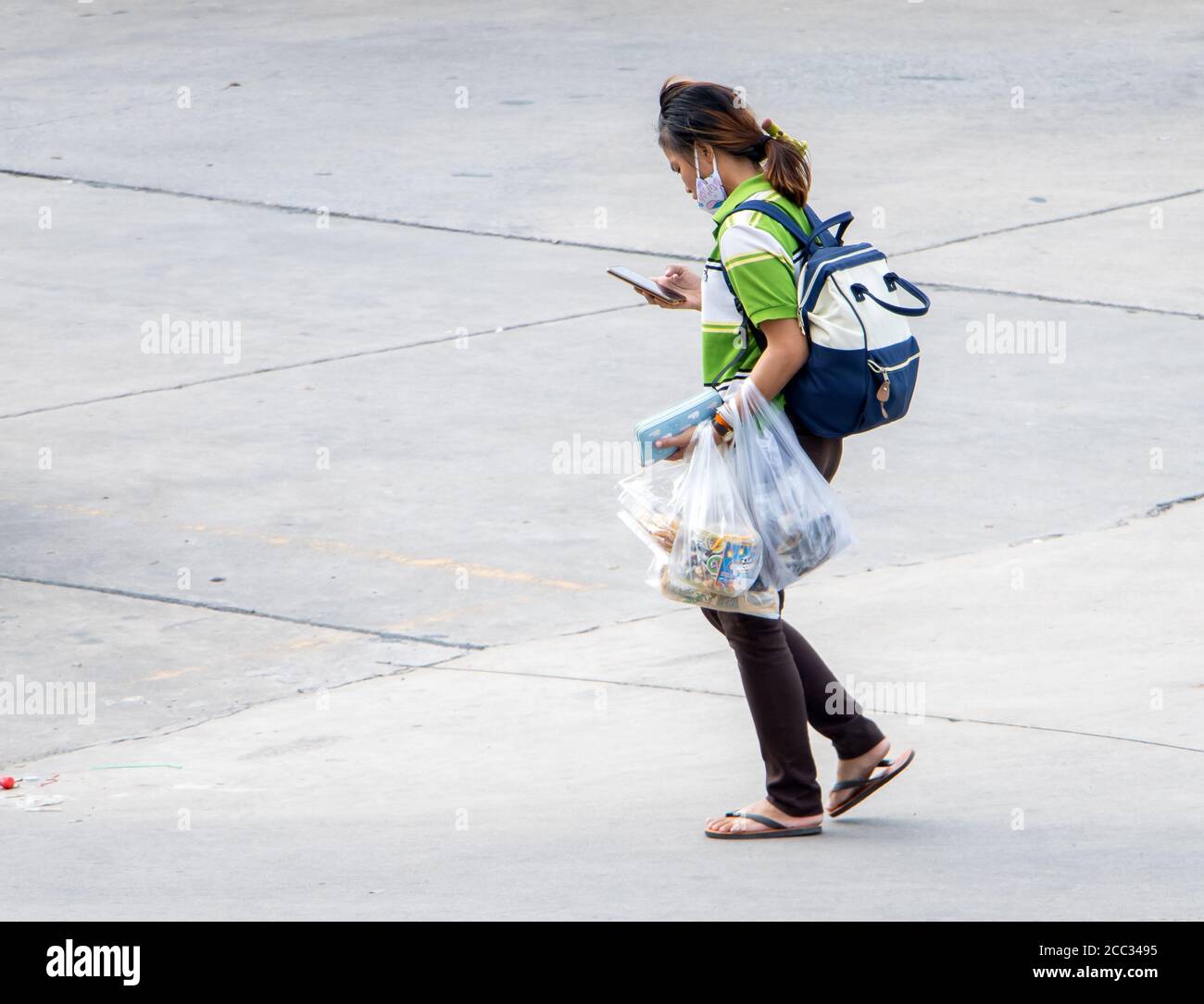 SAMUT PRAKAN, THAILAND, JULY 03 2020, A woman walks on the street and carries purchases in many plastic bags. Stock Photo