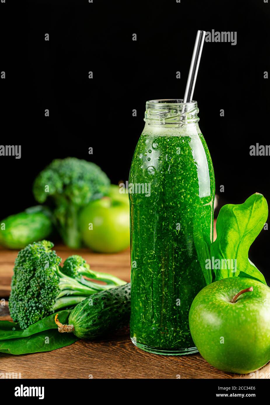 Bottle of green alkaline smoothie with ingredients on dark backdrop. Healthy eating and weight loss Stock Photo