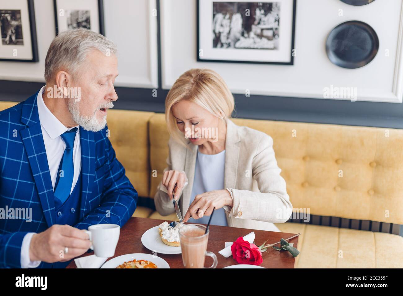 mature couple tasting yummy cake. close up photo. man and woman in stylish suits enjoying the dessert Stock Photo