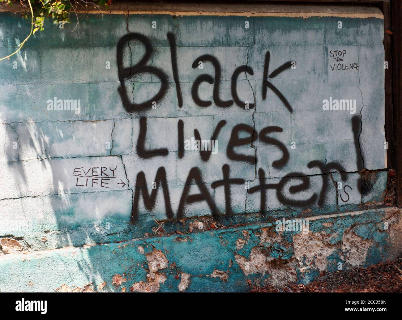 Graffiti words on cement wall by sidewalk. Black lives matter. Every Life. Stop the violence. Stock Photo