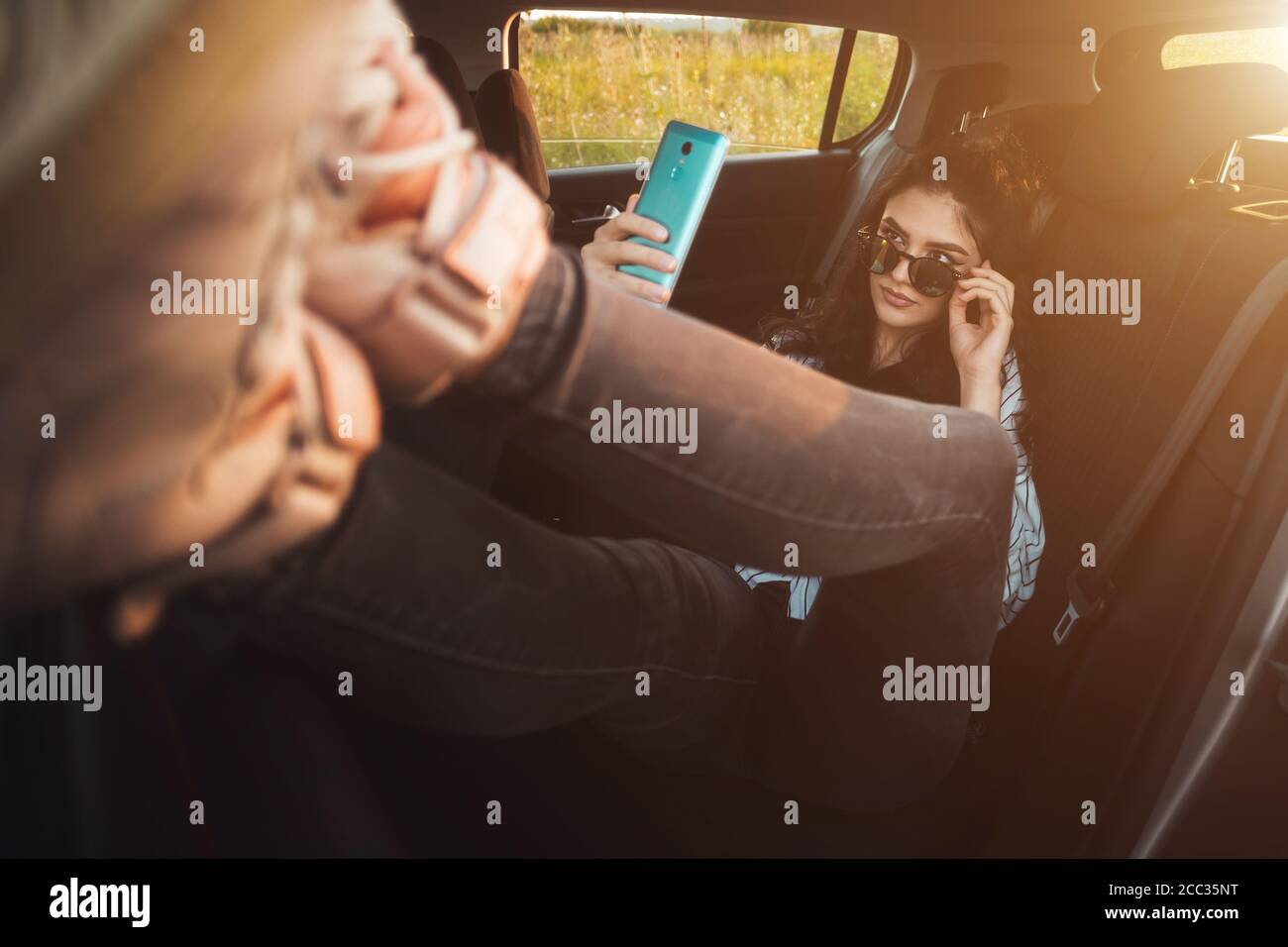 Beautiful young woman using mobile phone at back seat of car Stock Photo