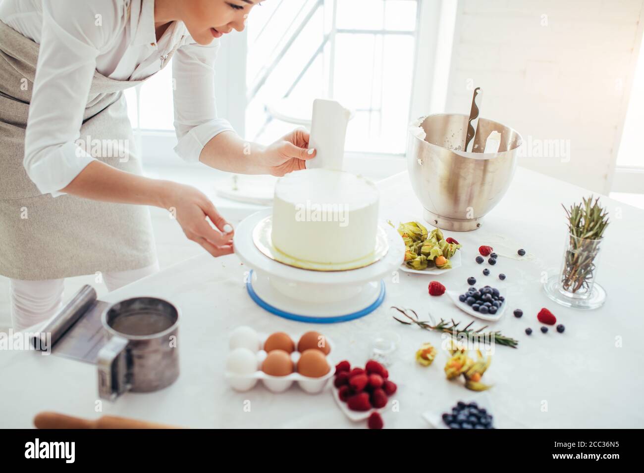 perfect smooth. chef holding a bench scraper vertically agains the cake