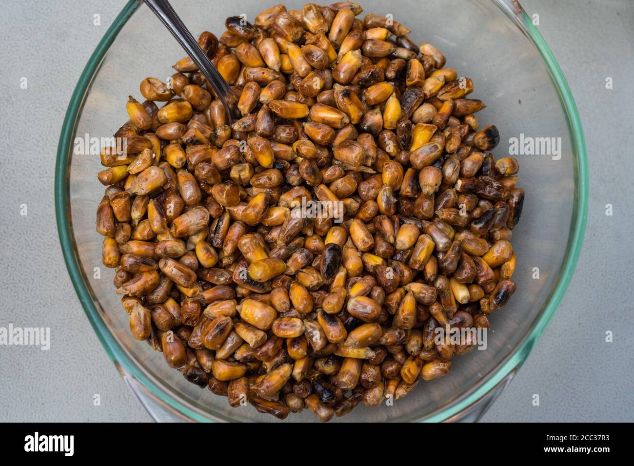 Top view of a glass bowl full of toasted Peruvian corn. Toasted canchita or chulpe corn often served alongside ceviche. Stock Photo