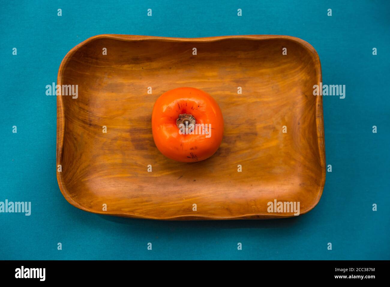Top view of persimmon fruit in a wood bowl and a blue background. Stock Photo