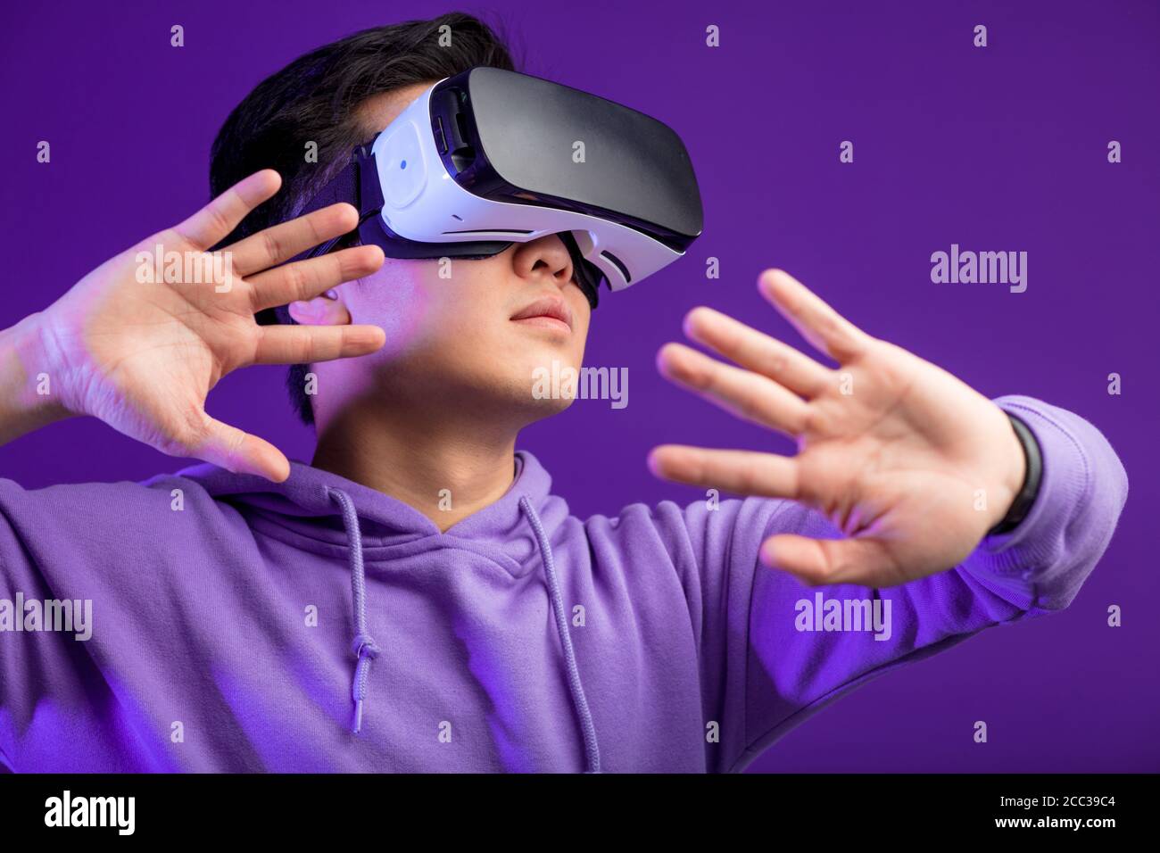 Young Asian man playing VR game in dark blue background. Chinese young  hipster wearing VR headset, half body shot. Young generation choose virtual  rea Stock Photo - Alamy