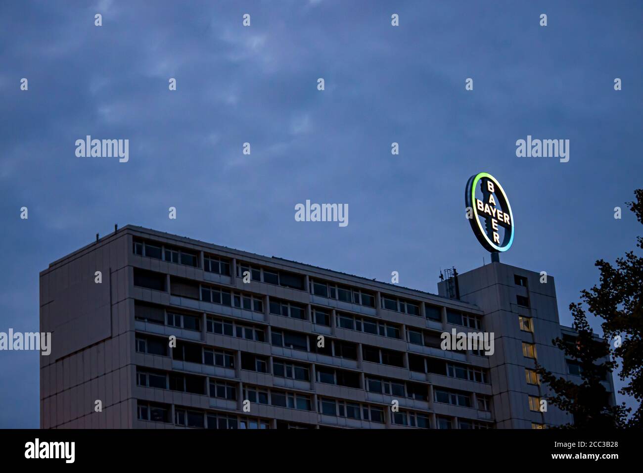 Berlin, Germany 09/14/2009:  isolated, night time view of the Bayer AG Pharma building with brand logo illuminated on top. Image also features silhoue Stock Photo