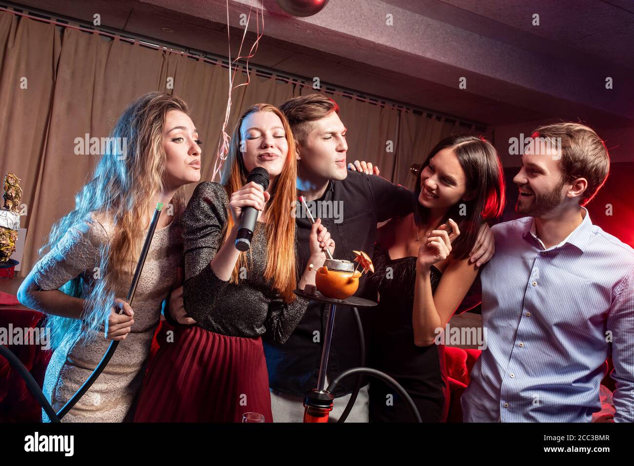 happy cheerful adults women and men spending day off in karaoke bar young ladies and guys wearing party clothes dresses. energetic and emotional gr Stock Photo Alamy