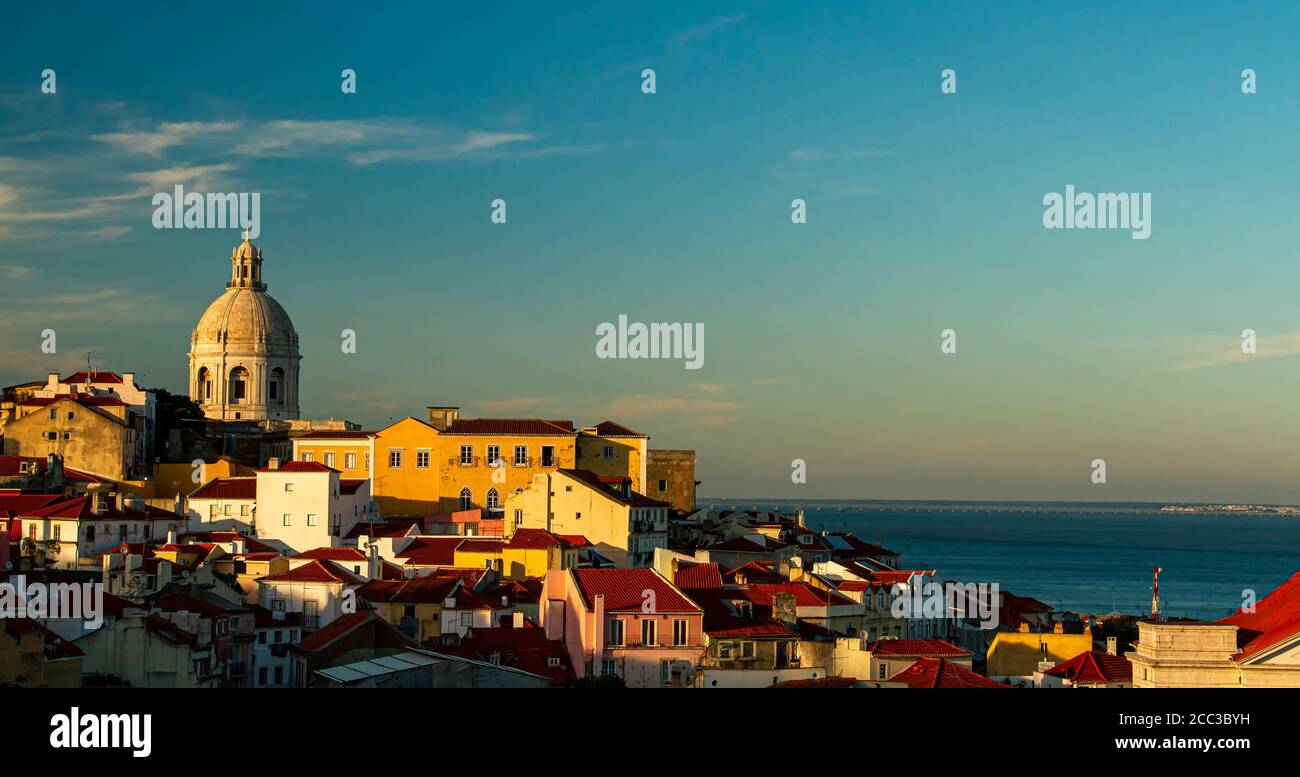 A sunset view of the historic Alfama district of Lisbon, Portugal. Image features the National Pantheon (the white dome overlooking the city), houses, Stock Photo