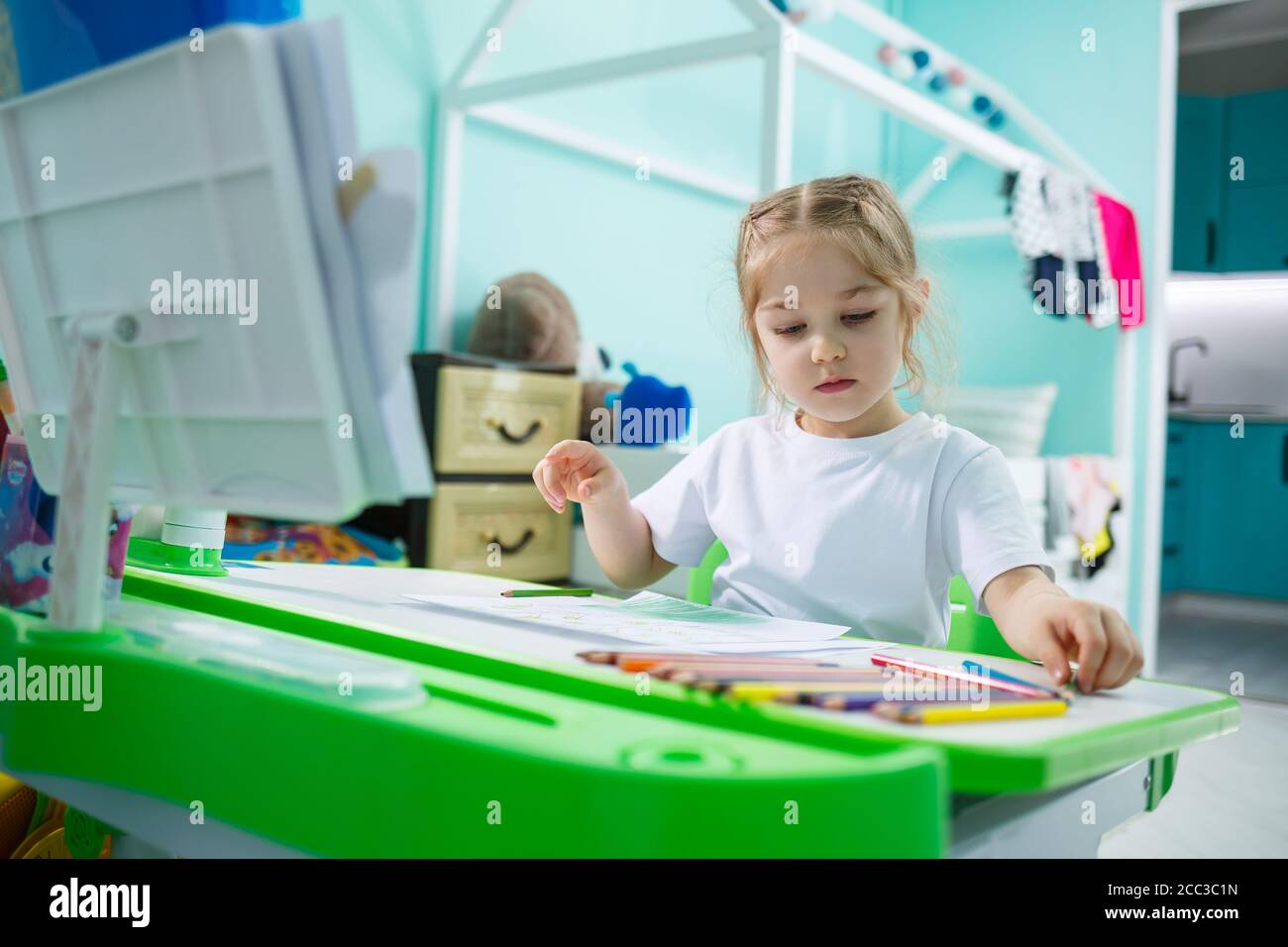 Portrait of a cute little girl looking at the camera and smiling while ...