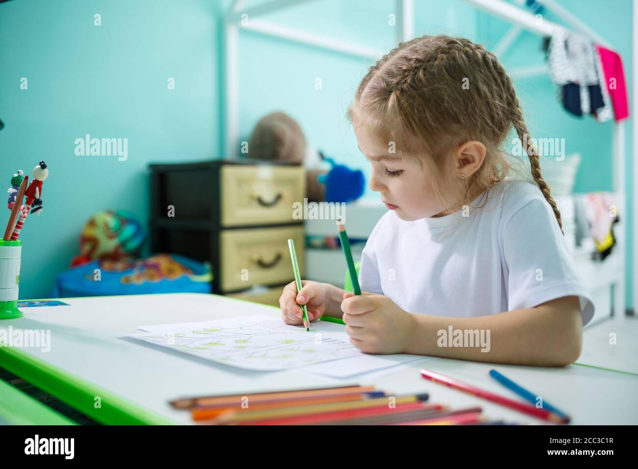 Portrait of a cute little girl looking at the camera and smiling while ...