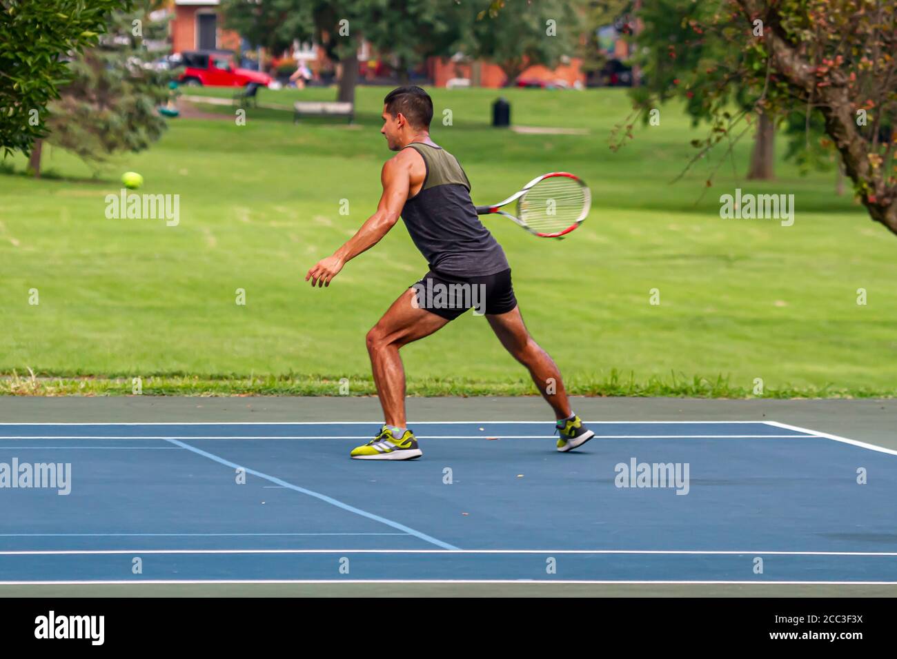 Maryland, USA 08/14/2020: An athletic hispanic man wearing short and sleeveless t shirt is playing tennis at a local court in Baker Park, Frederick. Stock Photo