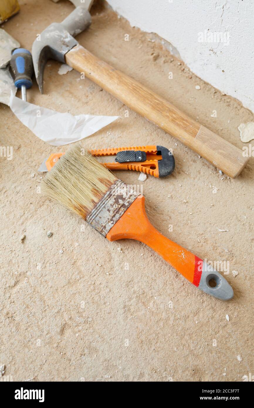 Tools for construction and repair lie on the concrete floor during repair  work with a spatula, hammer, tape measure. To make repairs. Selective focus  Stock Photo - Alamy