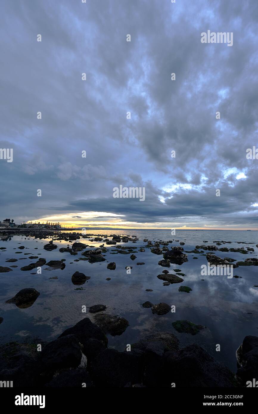 quiet flat seas under a dramatic brooding sky Stock Photo