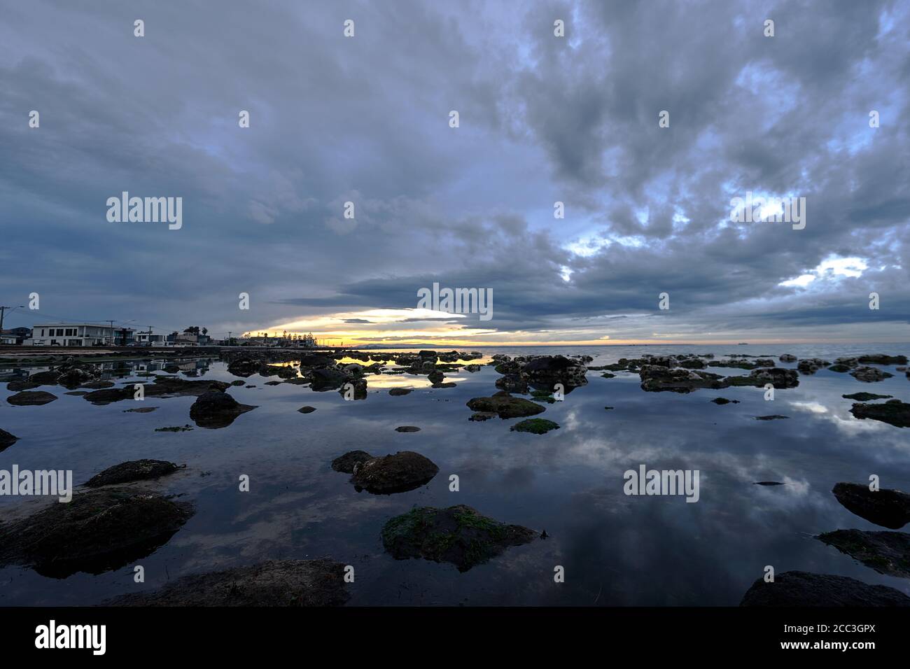 quiet flat seas under a dramatic brooding sky Stock Photo