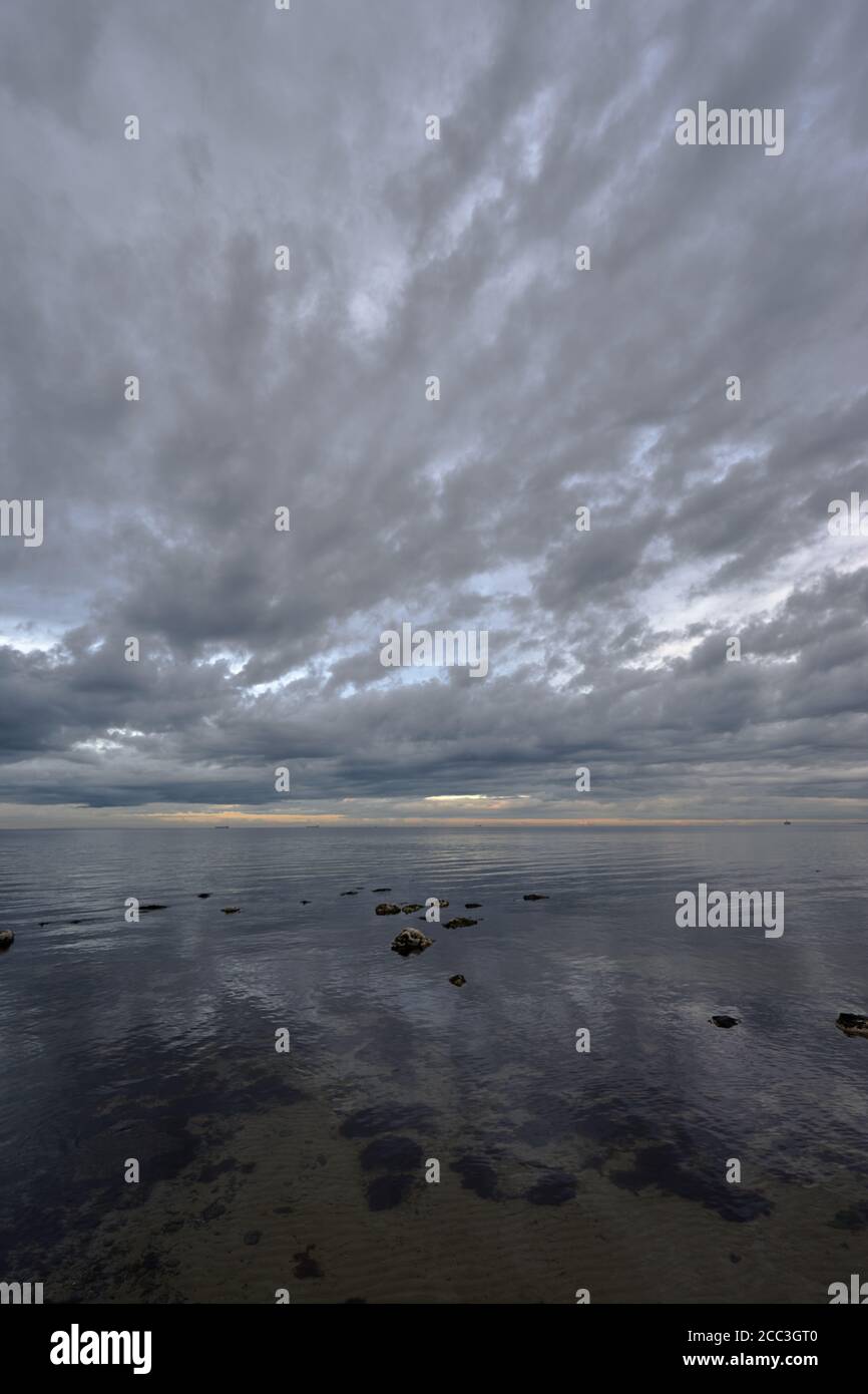 quiet flat seas under a dramatic brooding sky Stock Photo
