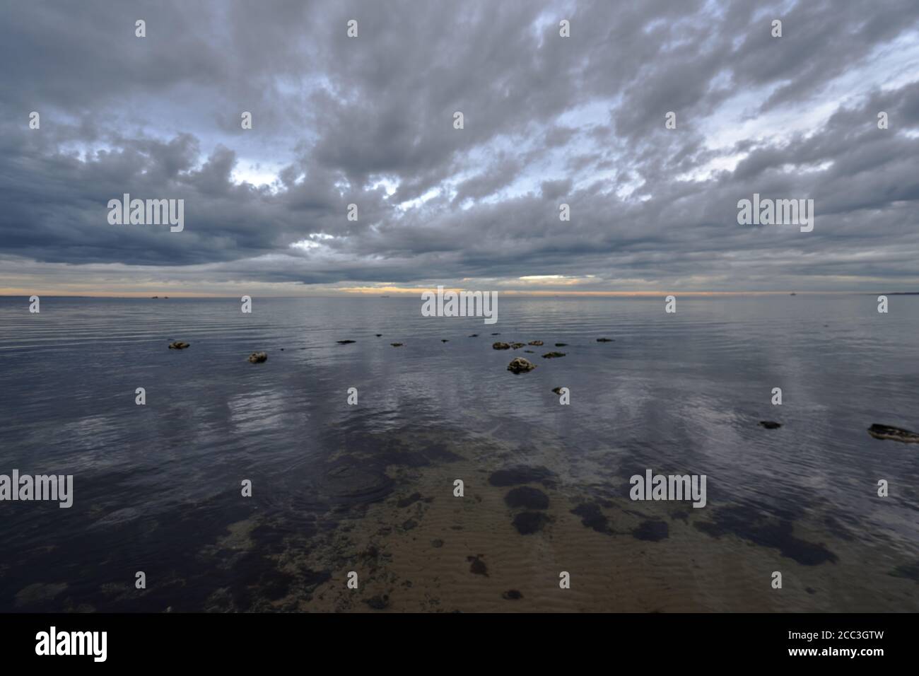 quiet flat seas under a dramatic brooding sky Stock Photo