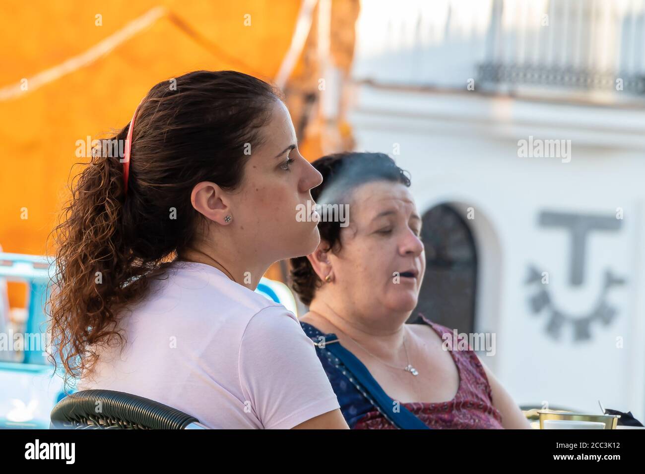Huelva, Spain - August 17, 2020: Woman is exhaling the smoke of a cigarette in a bar terrace Stock Photo