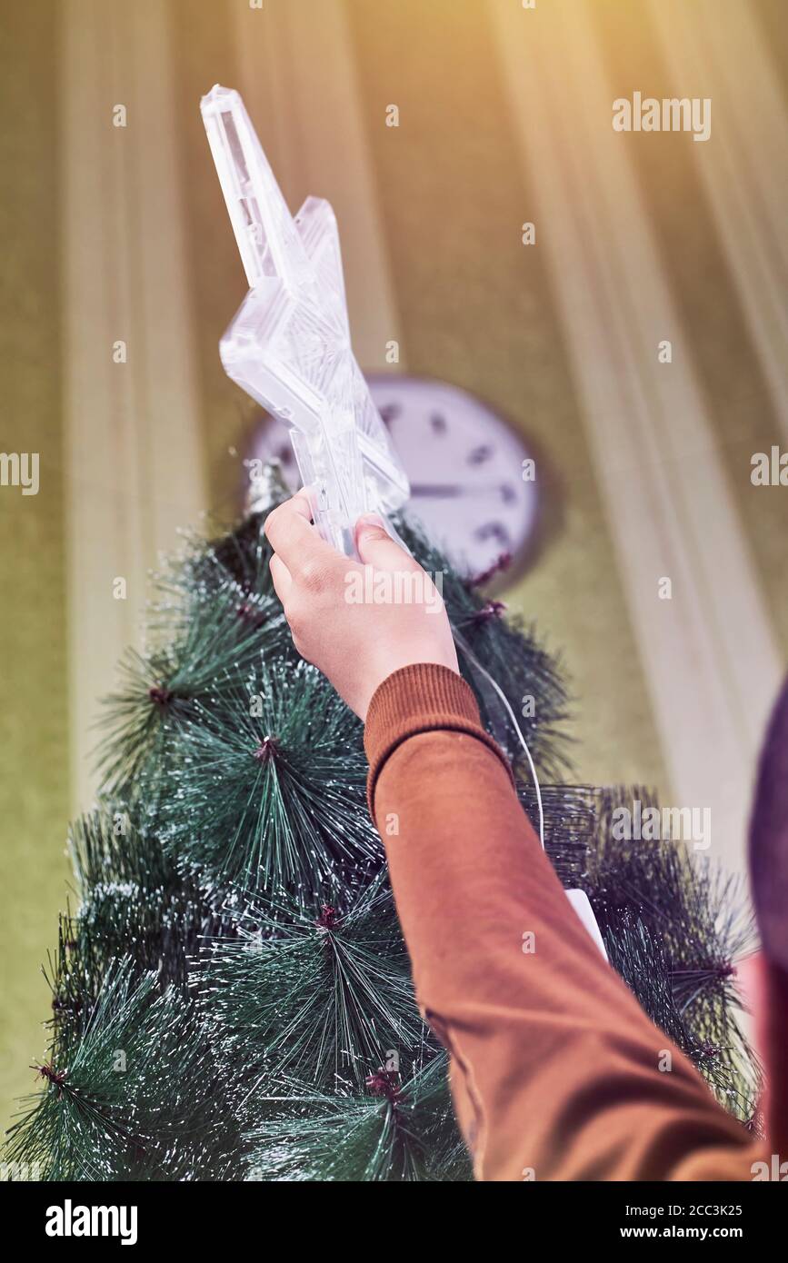Little boy trying to put the star on top of a Christmas tree Stock