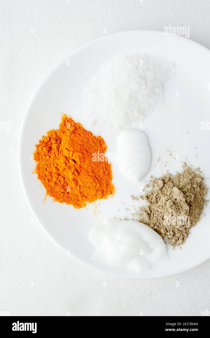 Creamy texture, salt, dry orange and light green powder pigmant for organic cosmetic on white plate background. Texture. Close-up. Top view, curcuma p Stock Photo