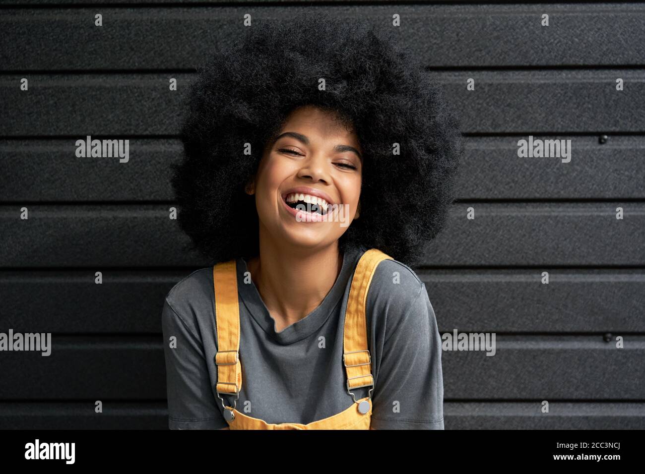 Happy African teen hipster girl with Afro hair laughing at camera, headshot. Stock Photo