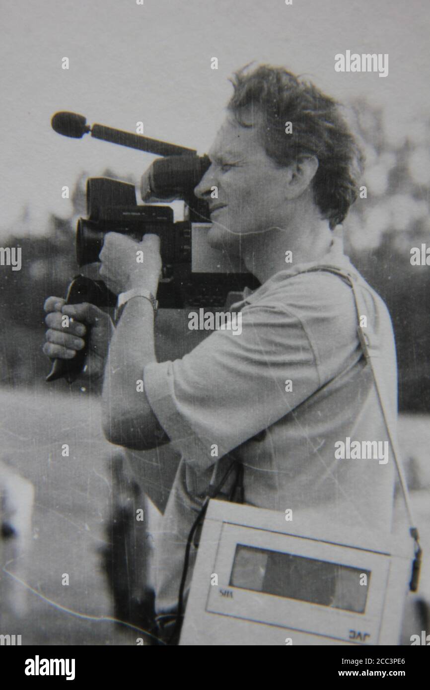 Fine 1970s vintage black and white photography of a photographer shooting some footage with an old movie camera. Stock Photo