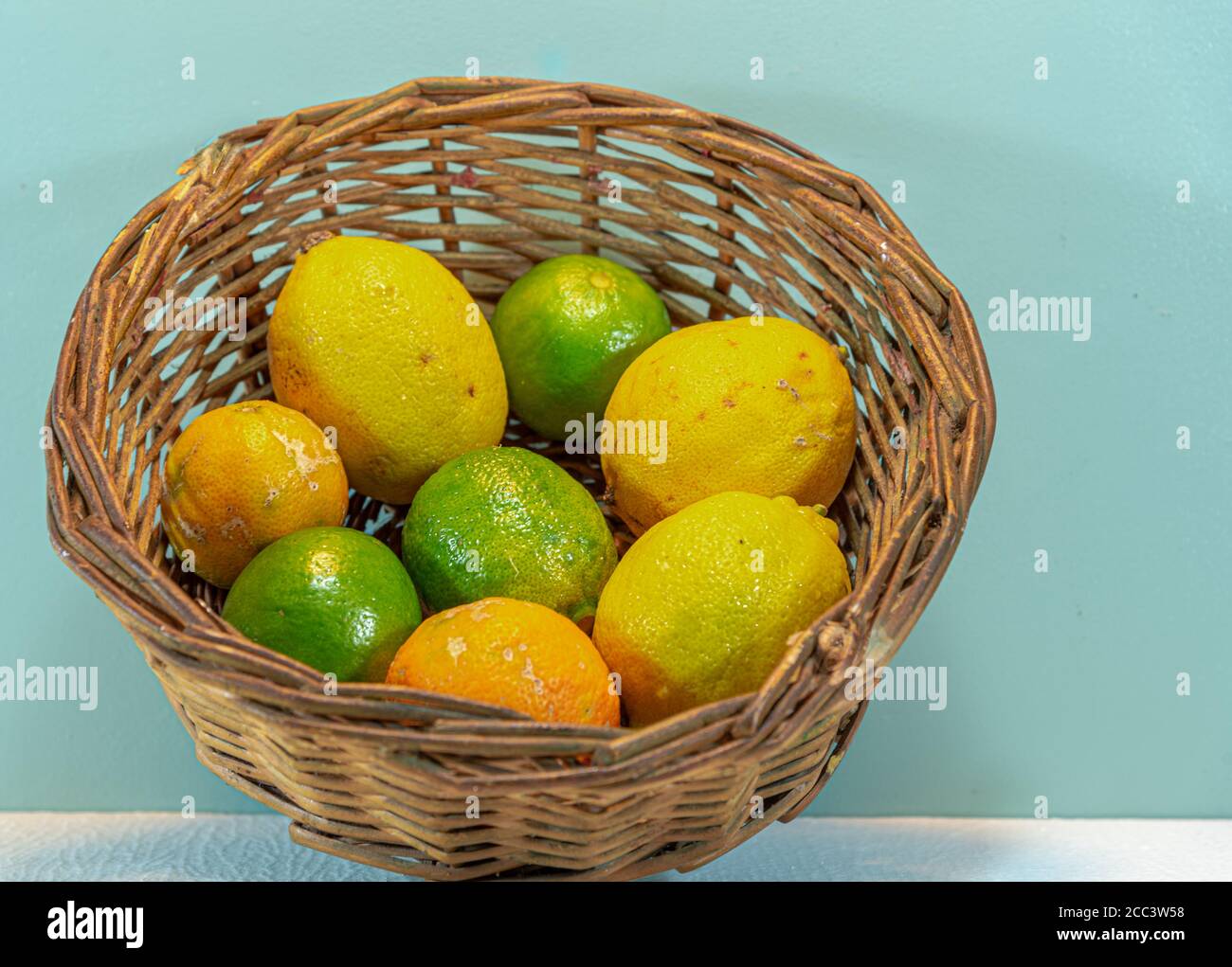 Wicker basket with lemon: Citrus limon. Citrus latifolia. Citrus × limonia. Sour fruit for juices. Source of vitamin C. Lemonade. Fresh fruits. Tropic Stock Photo