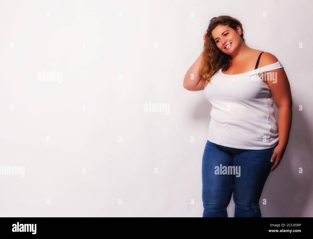 Beautiful blonde plus size model in sleeveless shirt and jeans Stock Photo -