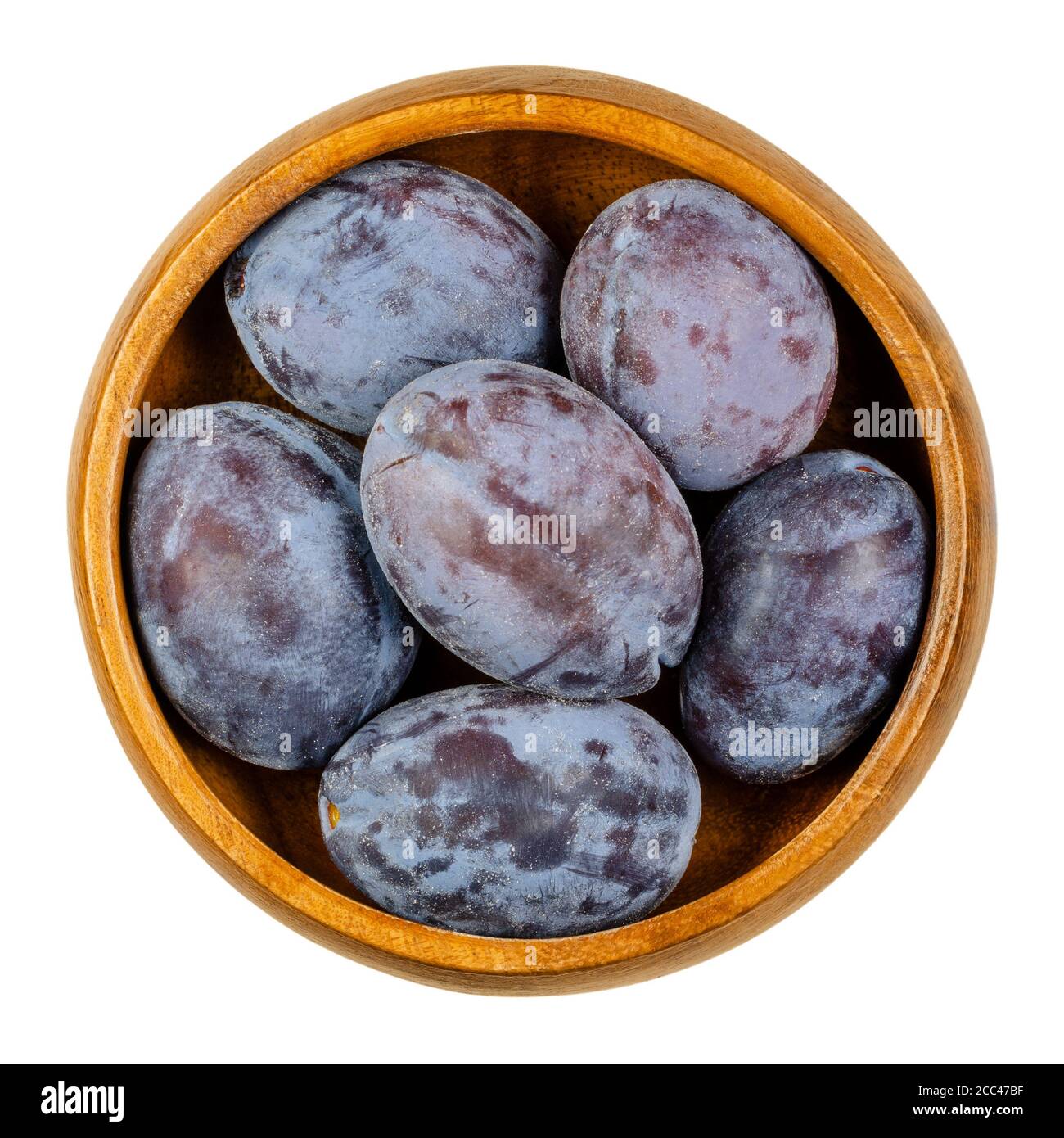 Zwetschge. Ripe European plums in wooden bowl. Freestone fruit with purple and violet skin. Popular seasonal table fruit in Central Europe. Prunus. Stock Photo