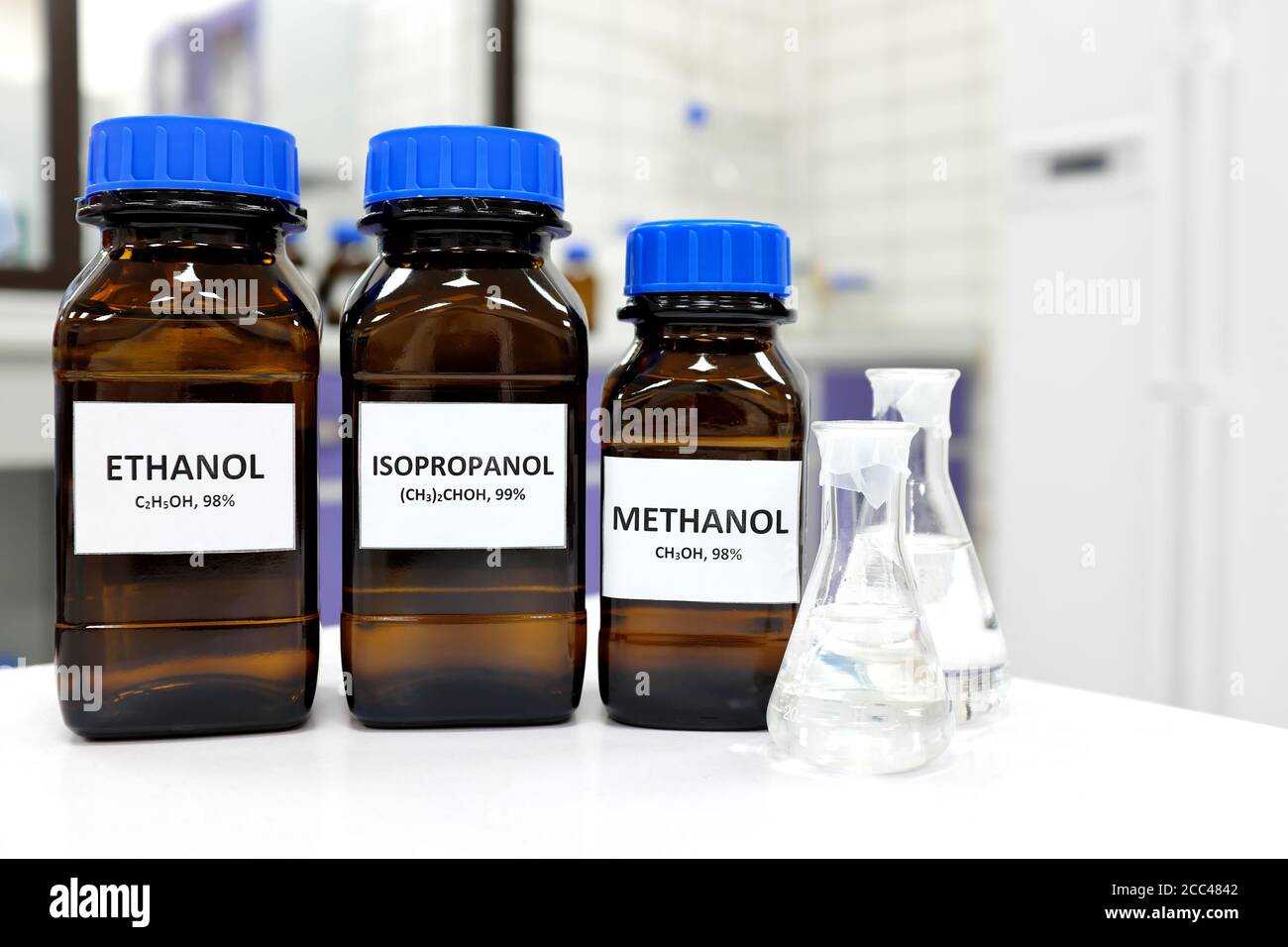 Selective focus of ethanol, methanol and isopropanol brown amber glass bottles inside a laboratory. Different types of alcohol. Stock Photo