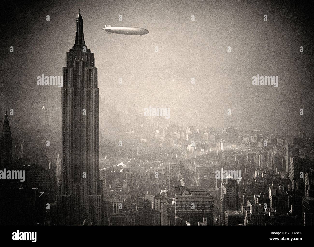 The German zeppelin Hindenburg floats past the Empire State Building over Manhattan, on August 8, 1936, en route to Lakehurst, New Jersey, from German Stock Photo
