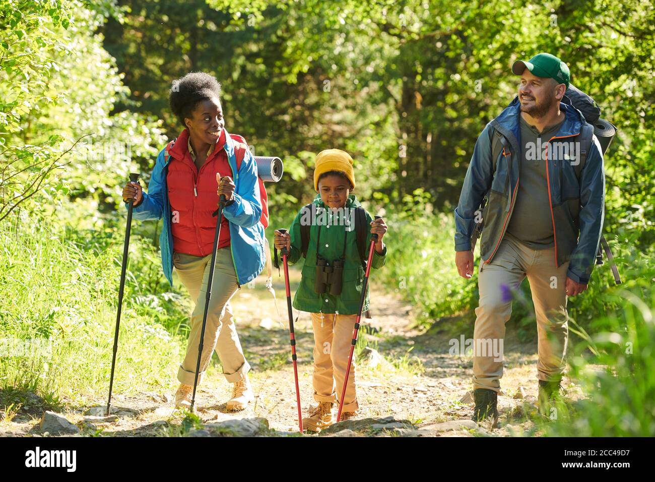 Multiethnic family of three walking in the forest together the go hiking Stock Photo