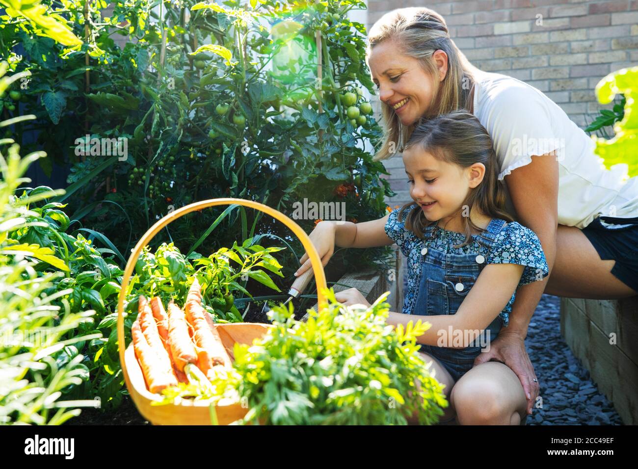 Mother And Daughter Digging In Raised Vegetable Beds At Home Stock Photo