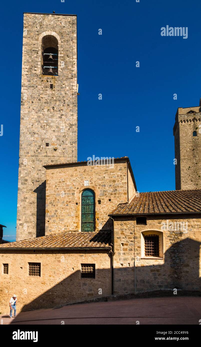 Picturesque scene of an old man with hat walking up a slope in the famous medieval hill town San Gimignano in Tuscany with the campanile della... Stock Photo