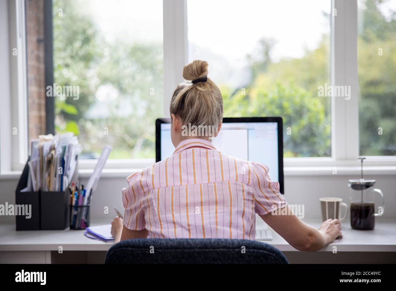Rear View Of Woman Working From Home On Computer  In Home Office Stock Photo