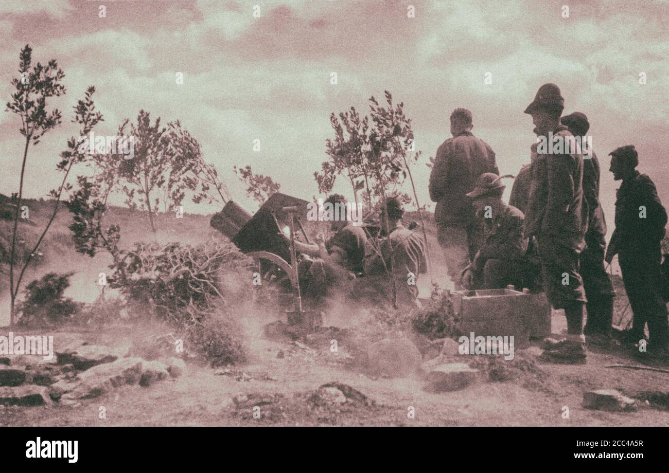 Italian mountain shooters (Alpini) are firing on the Greek troops from the cannon of a 75-mm mountain cannon 75/13. Bargullas, Albania. 1941 Stock Photo
