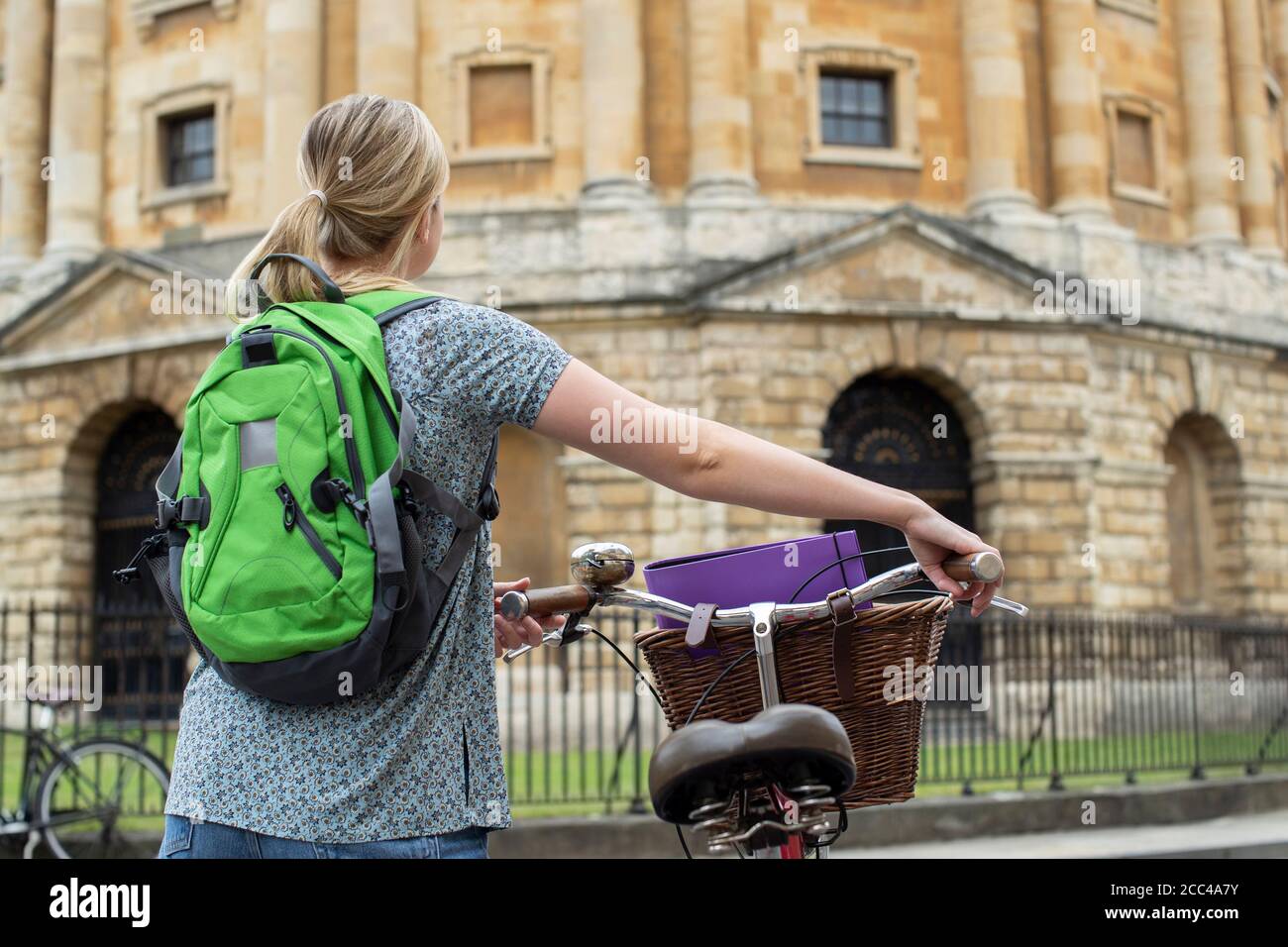 Rear View Of Female Student Riding Old Fashioned Bicycle Around Oxford University College Buildings By Radcliffe Camera In Radcliffe Square UK Stock Photo