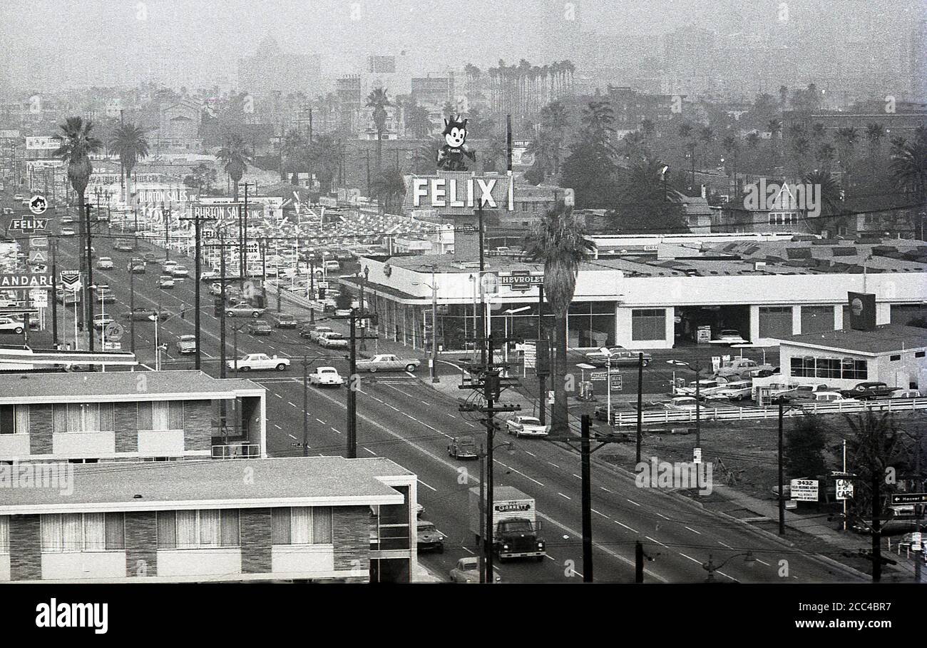 1964, historical, summertime and a view across a hazy Los Angles skyline, showing buildings, cars, road and a 'Felix' sign over a Chevrolet motorcar dealership. Stock Photo